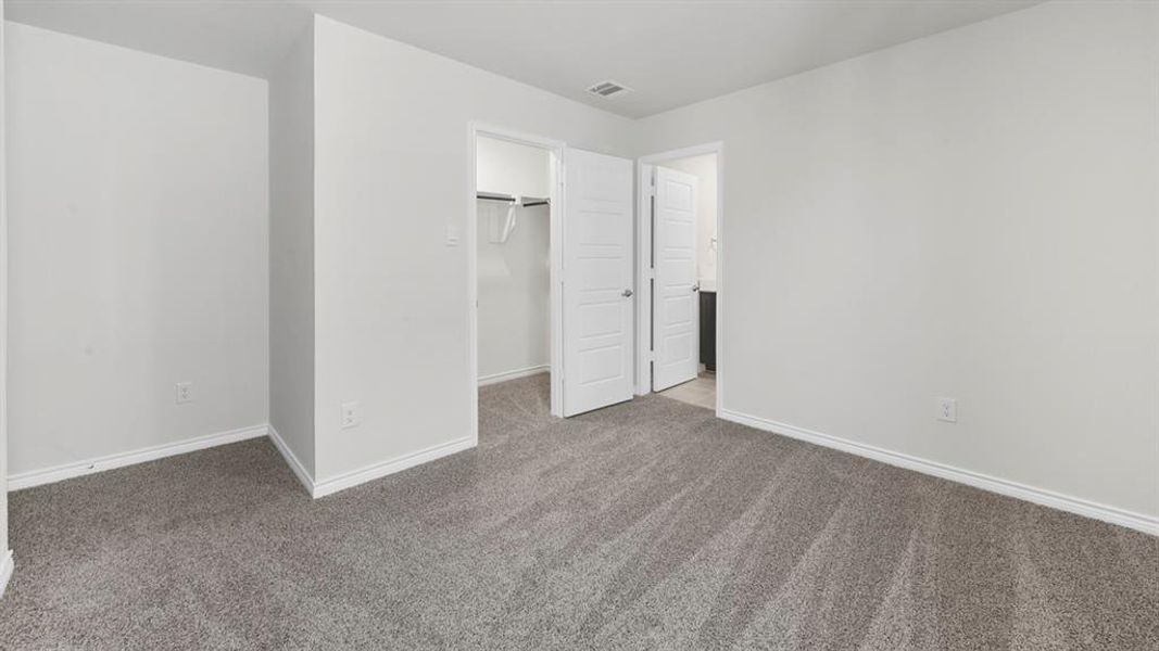 Unfurnished bedroom with a walk in closet and light colored carpet
