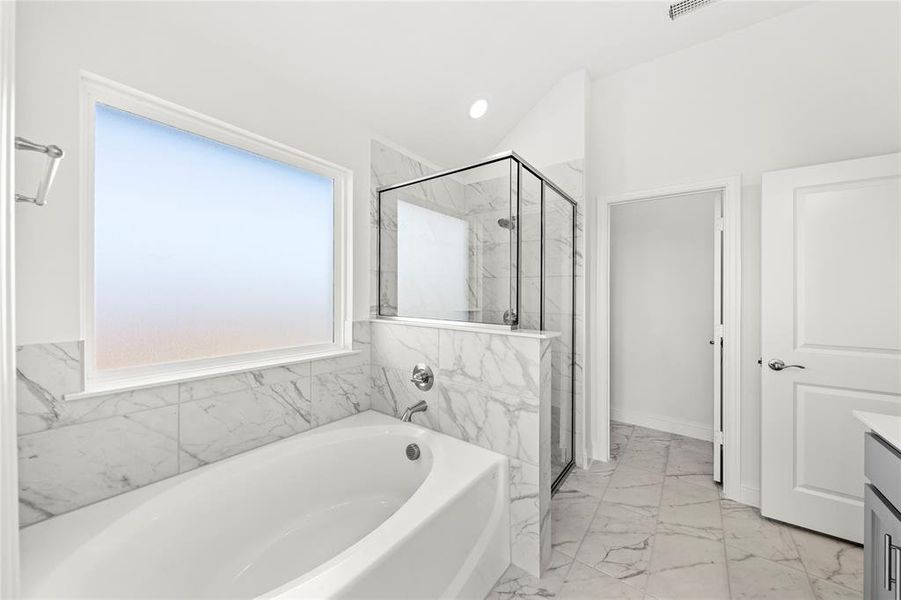 Primary suite bath offers garden tub and separate shower.