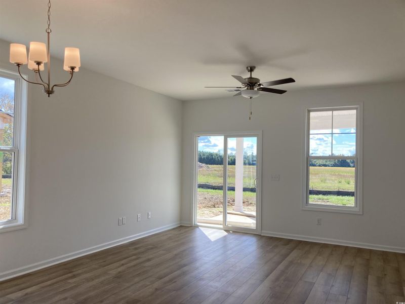 Unfurnished living room featuring dark wood-type flooring, a chandelier, and ceiling fan