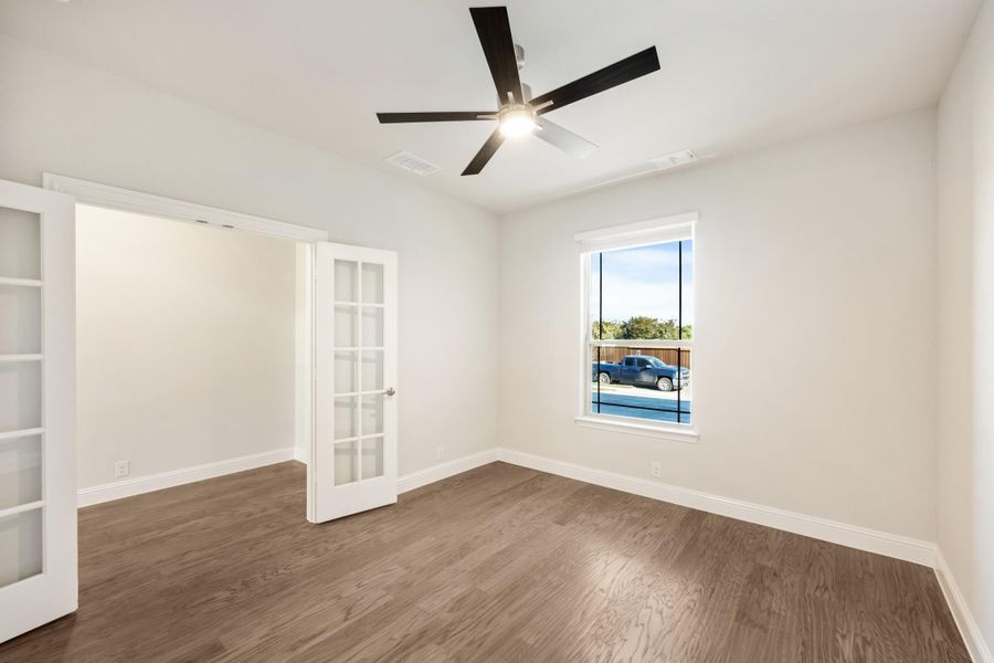 Empty room with hardwood floors, ceiling fan, and French doors leading to a closet Empty room with hardwood floors, ceiling fan, and French doors leading to a closet