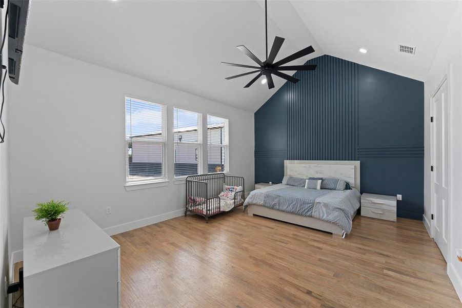Bedroom featuring light wood-style floors, a ceiling fan, and high vaulted ceiling Bedroom featuring light wood-style floors, a ceiling fan, and high vaulted ceiling