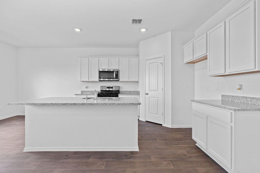 Kitchen with light stone counters, white cabinetry, dark wood-style floors, recessed lighting, and appliances with stainless steel finishes Kitchen with light stone counters, white cabinetry, dark wood-style floors, recessed lighting, and appliances with stainless steel finishes