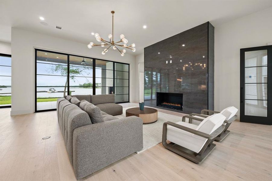 Living area featuring a chandelier, light wood-style flooring, a fireplace, and recessed lighting Living area featuring a chandelier, light wood-style flooring, a fireplace, and recessed lighting