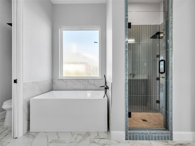 Bathroom with marble look tiles, a soaking tub, and a shower stall Bathroom with marble look tiles, a soaking tub, and a shower stall