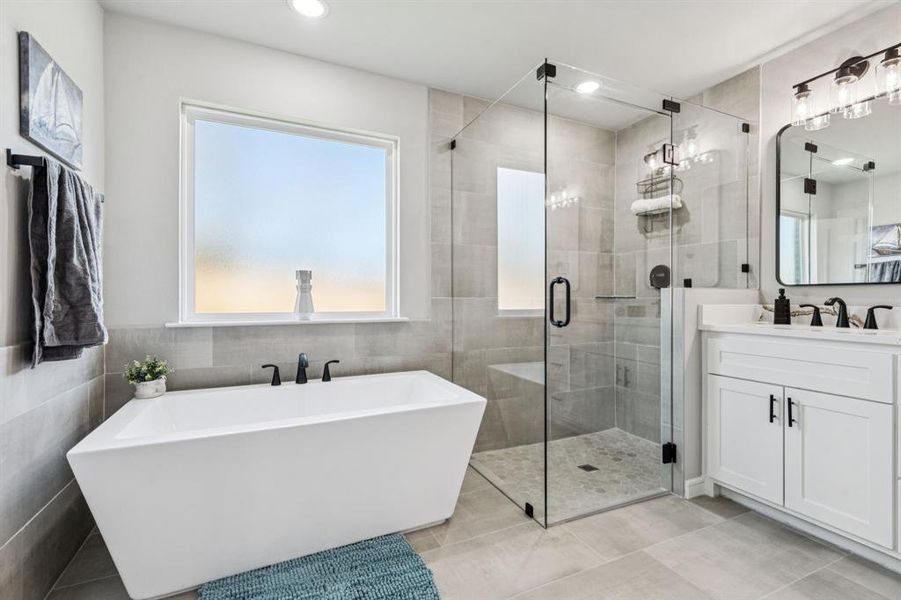 Bathroom featuring a freestanding tub, vanity, a stall shower, tile walls, and recessed lighting