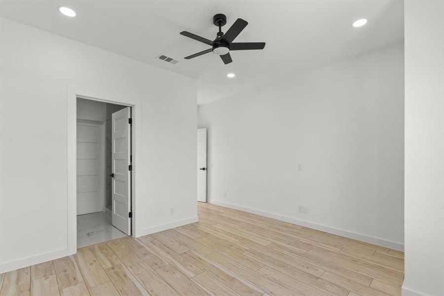 Primary bedroom with recessed lighting, wood finished floors, a ceiling fan, baseboards, and visible vents