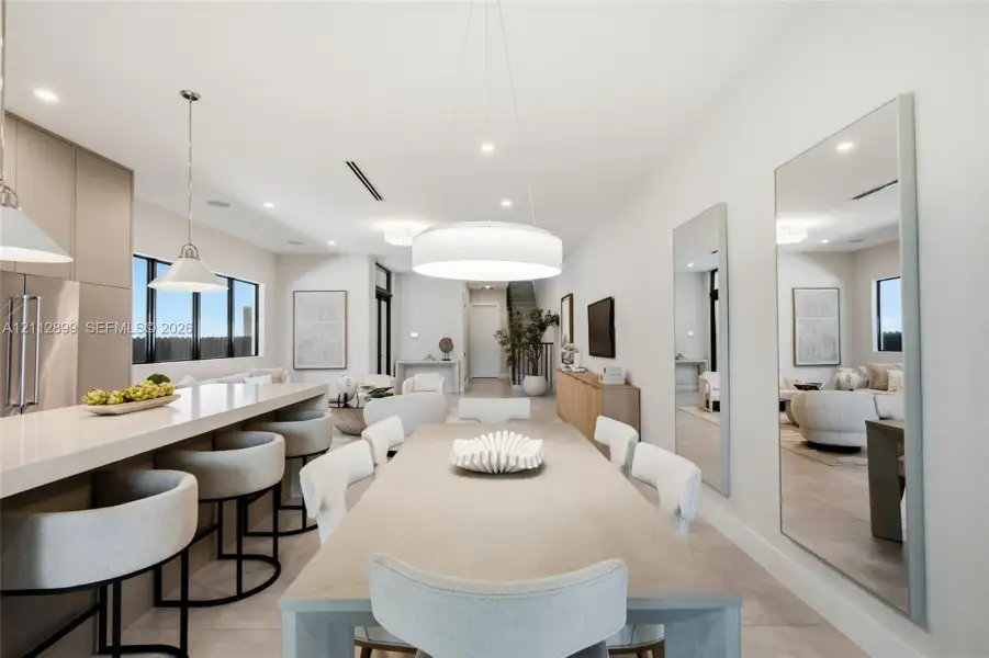 Open-concept interior featuring a kitchen island with stone countertop, large-scale drum pendant lighting, flush-mount recessed ceiling lights, and wall-to-wall mirrors