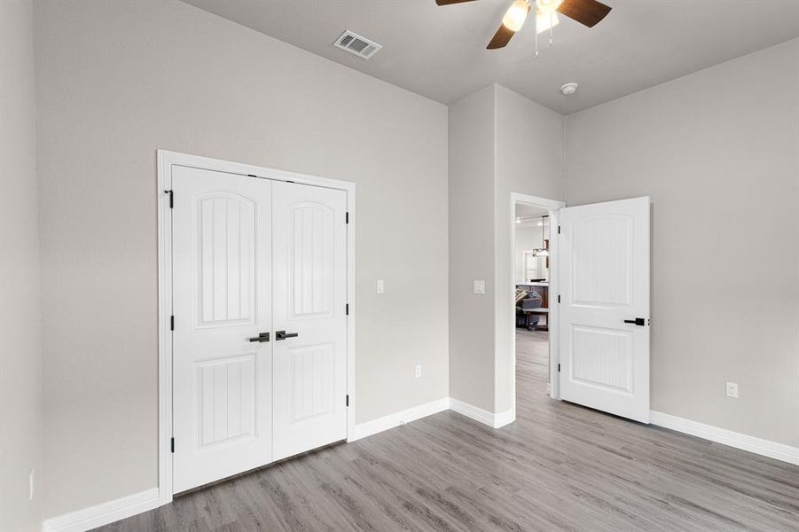 Unfurnished bedroom with light wood-type flooring, a ceiling fan, and a closet