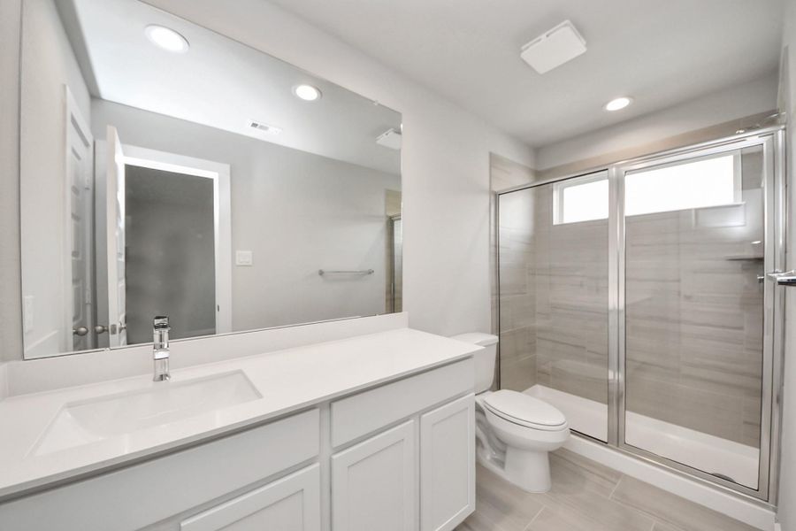 Secondary bath features tile flooring, Sample photo of completed home with similar floor plan. Actual colors and selections may vary.walk-in shower with tile surround, light stained wood cabinets, beautiful light countertop. Secondary bath features tile flooring, Sample photo of completed home with similar floor plan. Actual colors and selections may vary.walk-in shower with tile surround, light stained wood cabinets, beautiful light countertop.