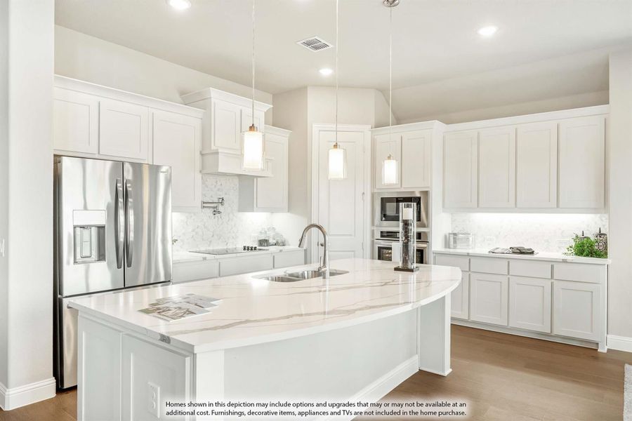 White kitchen with large curved island, quartz countertops, pendant lights, and stainless steel appliances