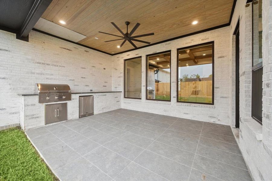 The covered outdoor patio boasts tongue and groove wood ceilings, an outdoor kitchen with leathered granite countertops, a ceiling fan, recessed LED lights, and large porcelein tiles. It's the perfect spot for entertaining!