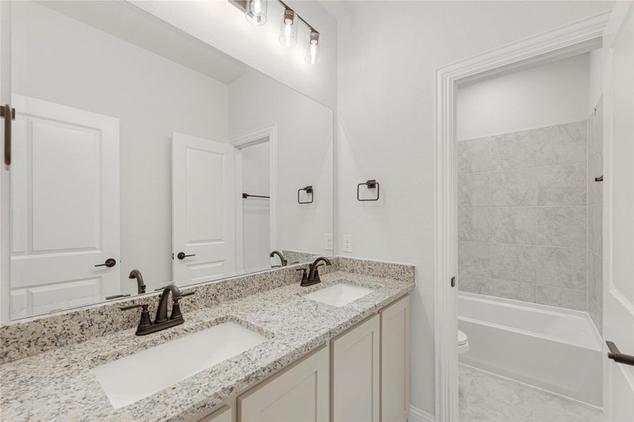 Bathroom with double sink vanity, granite countertop, and tiled tub-shower combo Bathroom with double sink vanity, granite countertop, and tiled tub-shower combo