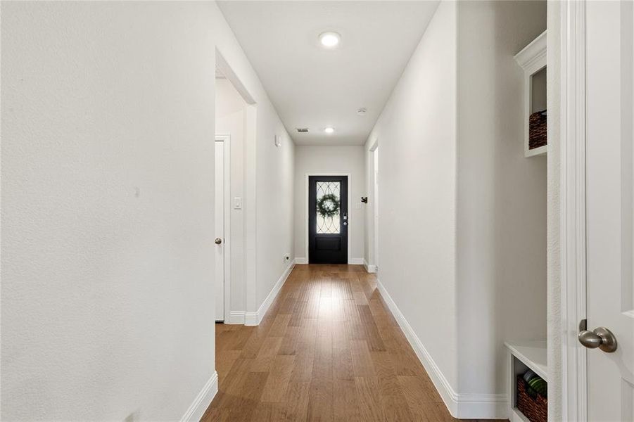 Long hallway featuring wood-finish flooring, recessed lighting, and white baseboards