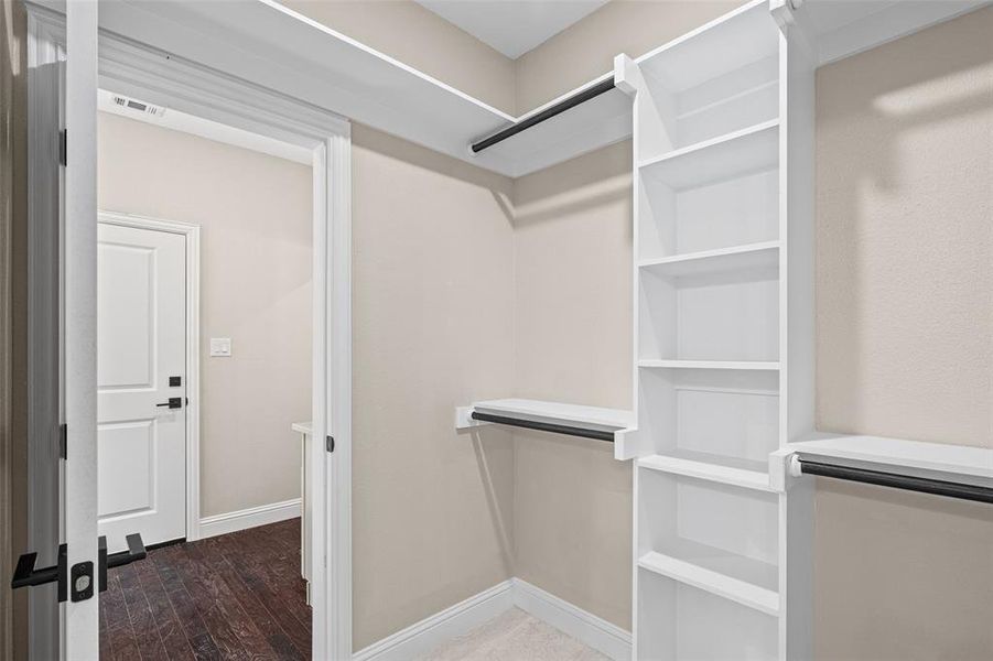 Walk-in closet featuring built-in shelving, hanging rods, and light-toned walls