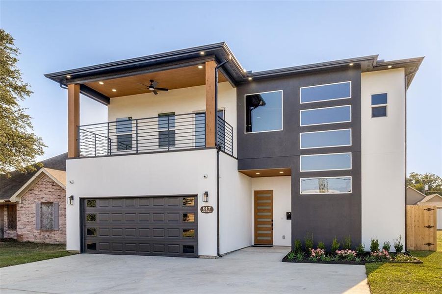 Contemporary home featuring stucco siding, a balcony, and a garage Contemporary home featuring stucco siding, a balcony, and a garage