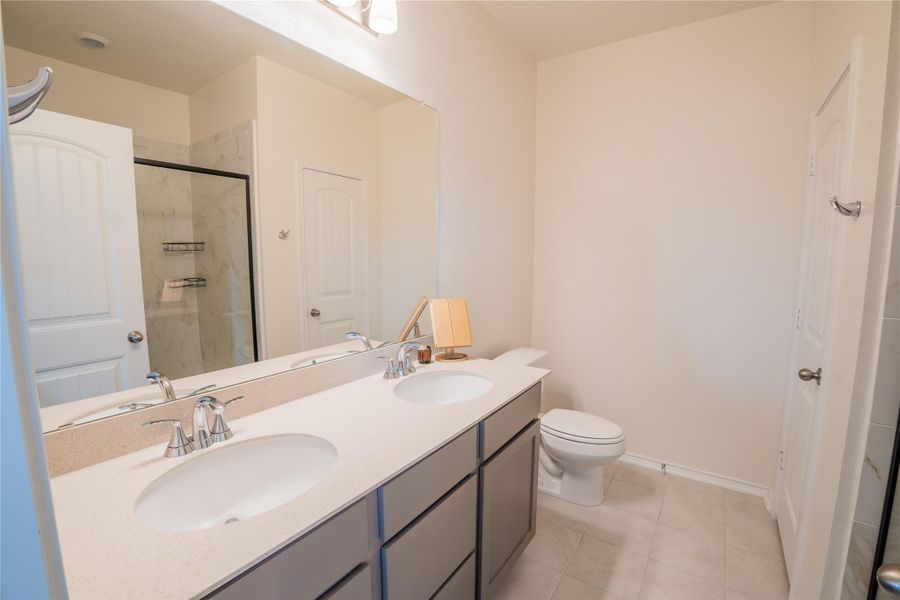 Bathroom vanity featuring a dual sink countertop, chrome fixtures, and grey cabinetry Bathroom vanity featuring a dual sink countertop, chrome fixtures, and grey cabinetry