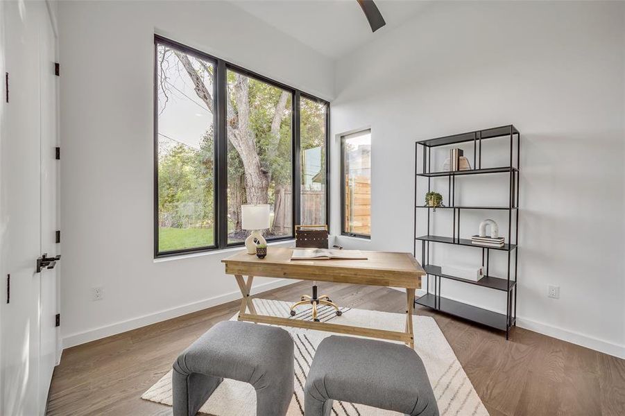 Main level bedroom at front of the home is a bright and versatile room with serene garden views, perfect as a home office or an inspiring guest bedroom.