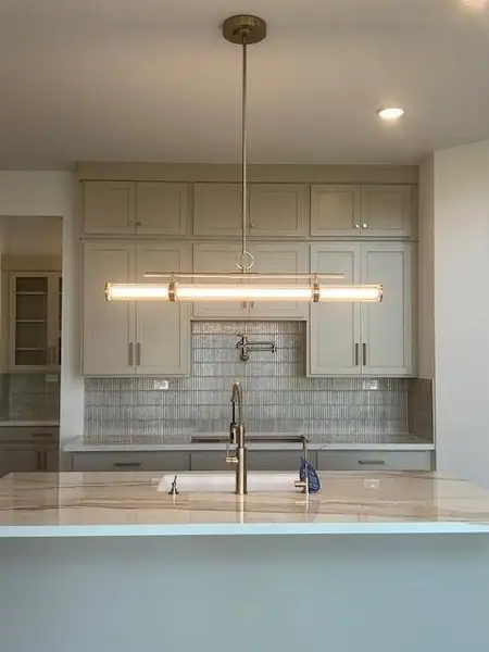 Modern pendent lighting plus the pot filler is a cook's dream kitchen