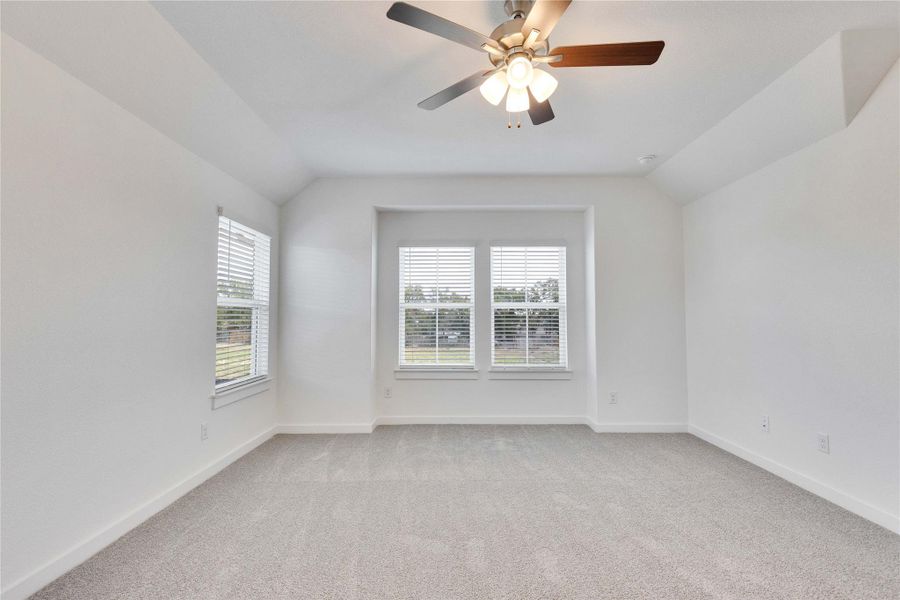 Spare room featuring plenty of natural light, light carpet, lofted ceiling, and a ceiling fan Spare room featuring plenty of natural light, light carpet, lofted ceiling, and a ceiling fan