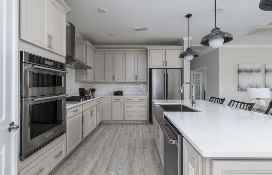 Large Kitchen with modern pendant lighting, kitchen island with a deep sink bowl, and a wall oven.