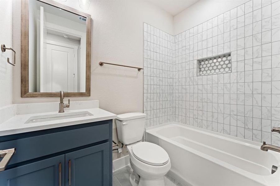 Full bathroom with tiled shower / bath, vanity, and toilet