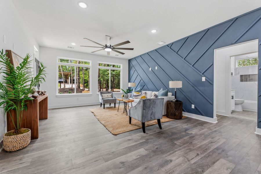 This living area features a bold accent wall and generous windows overlooking a lush, wooded landscape.