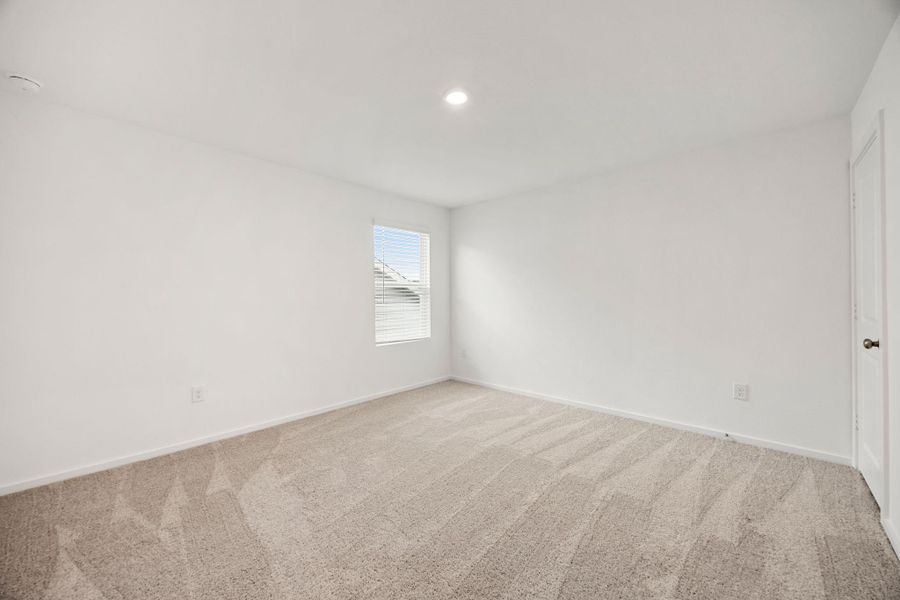 Bright and spacious secondary bedroom featuring neutral finishes, plush carpet, and a large window that fills the room with natural light.