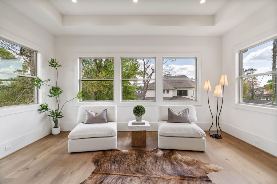 A serene extension of the primary suite, this sitting area is framed by multiple windows that fill the space with natural light. Clean lines and elevated ceilings create an open, airy retreat with views of the surrounding neighborhood.