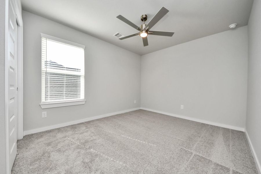 Secondary bedroom features plush carpeting, large windows that let in plenty of natural light, bright paint, and spacious closets. Sample photo of completed home with similar floor plan. Actual colors and selections may vary.