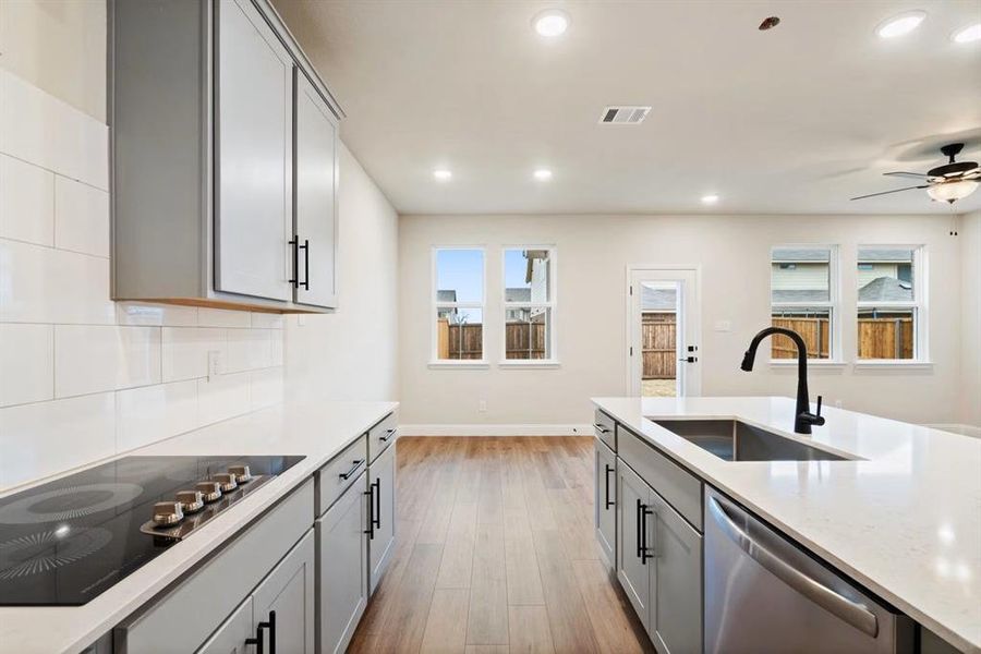 Kitchen with gray cabinets, dishwasher, sink, and black electric cooktop