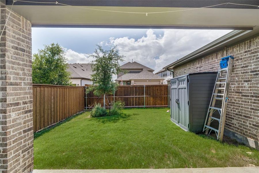 Private backyard featuring a manicured lawn, full wood privacy fencing, and brick exterior walls