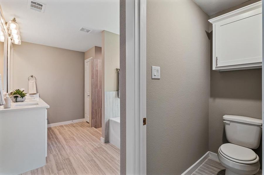 Bathroom featuring hardwood / wood-style flooring, a washtub, toilet, and vanity