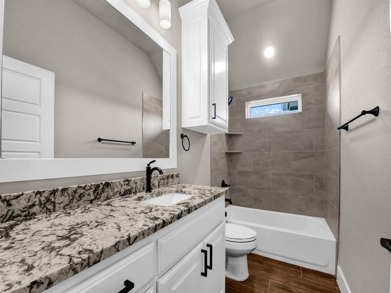 Bathroom featuring vanity, shower / bath combination, and wood finish floors