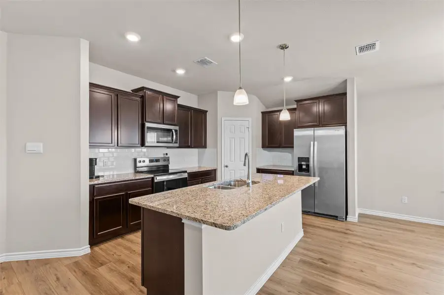 Kitchen featuring backsplash, dark brown cabinets, stainless steel appliances, decorative light fixtures, and recessed lighting