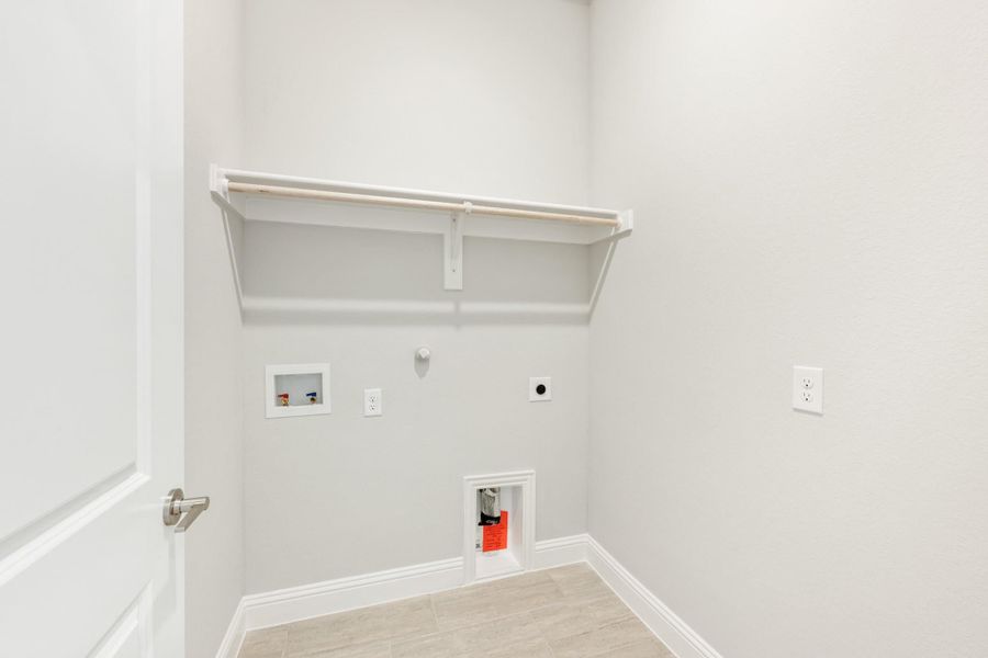 Laundry room with wall-mounted shelf, washer and dryer hookups, and tile floor Laundry room with wall-mounted shelf, washer and dryer hookups, and tile floor