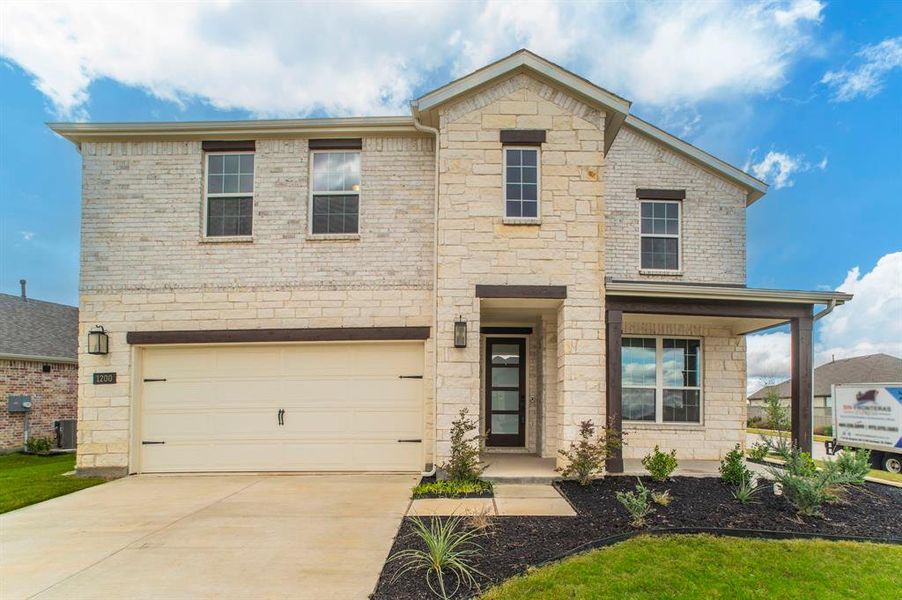 View of front facade with stone siding, a garage, driveway, a porch, and brick siding View of front facade with stone siding, a garage, driveway, a porch, and brick siding