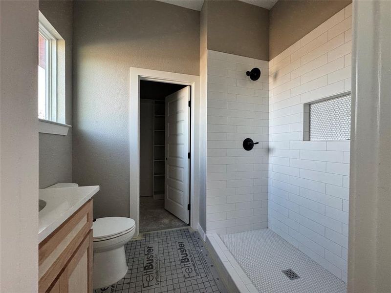 Bathroom with tile patterned flooring, vanity, toilet, and a tile shower