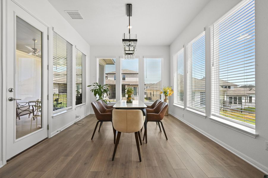 Sunlight streams through multiple windows onto the wood flooring of this dining area.