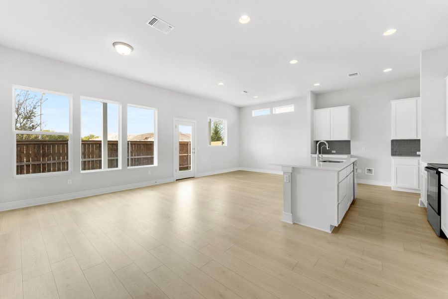 A spacious, naturally illuminated room featuring a contemporary kitchen island and light-toned flooring. A spacious, naturally illuminated room featuring a contemporary kitchen island and light-toned flooring.