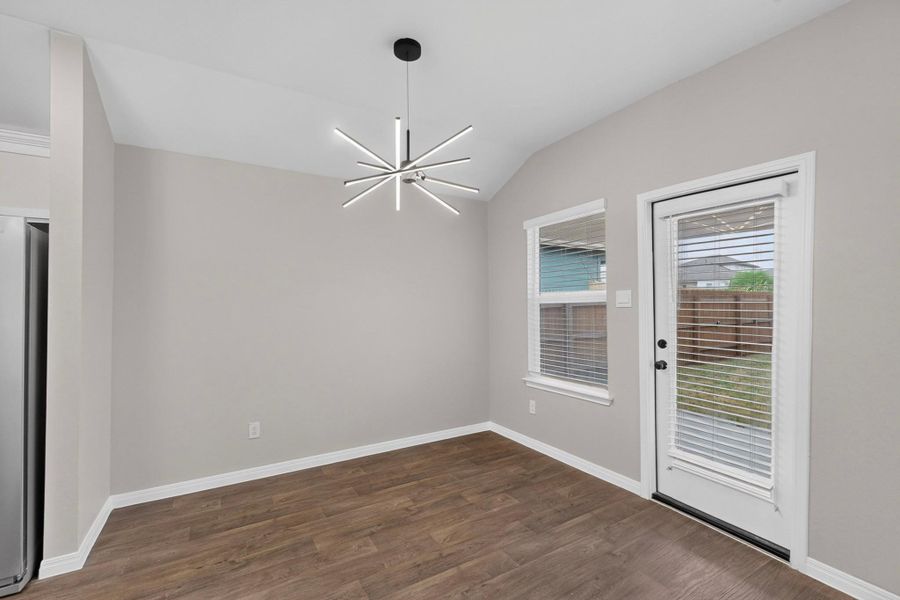 A vaulted ceiling and wood-look flooring enhance this inviting breakfast area with backyard access.