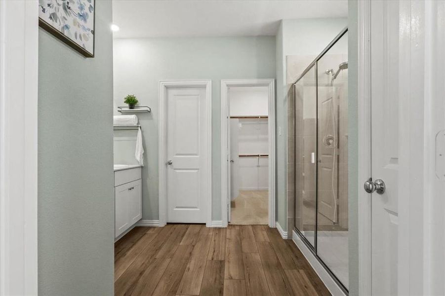 Full bath featuring a shower stall, wood finished floors, vanity, and a walk in closet Full bath featuring a shower stall, wood finished floors, vanity, and a walk in closet