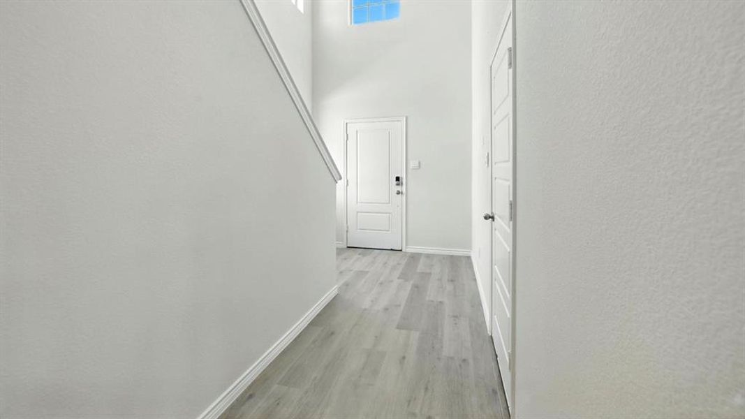Hallway with a towering ceiling and light wood-style flooring