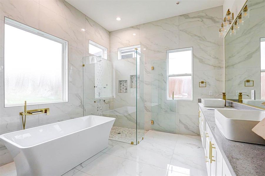 Primary Bathroom featuring plenty of natural light, vanity, independent shower and bath, and tile walls