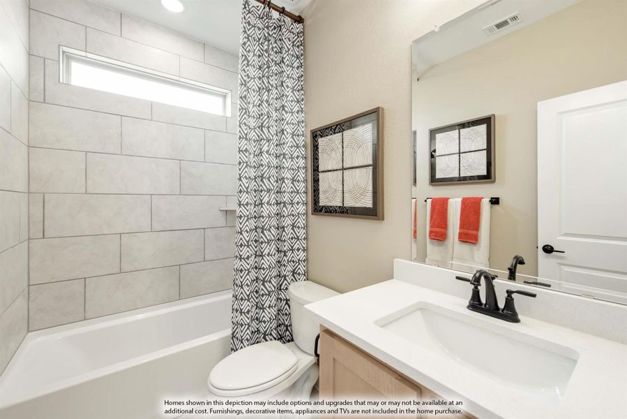 Bathroom with tiled tub-shower combo, white countertop vanity, and patterned shower curtain