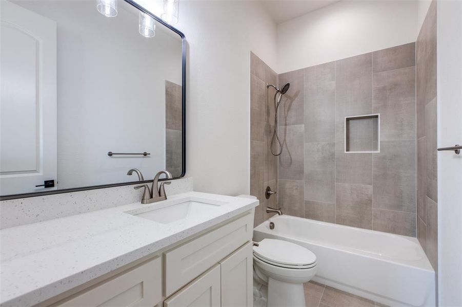 Full bathroom with tile patterned floors, tiled shower / bath combo, vanity, and toilet