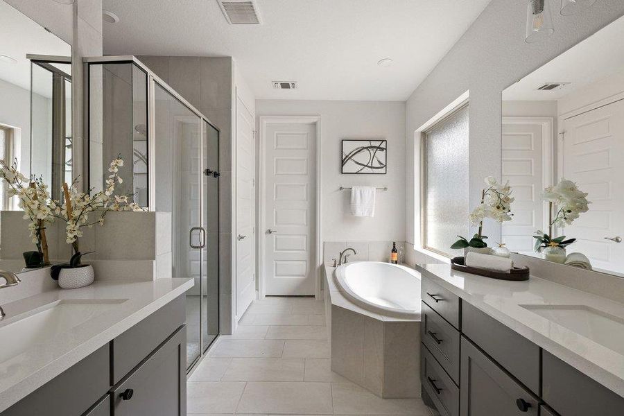 Luxurious bathroom with dual vanities, a glass-enclosed shower, and a pristine soaking tub for ultimate relaxation.