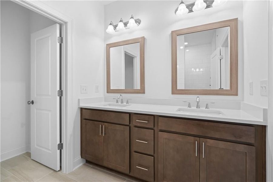 The primary bathroom exudes elegance and spa-like comfort, featuring a dual vanity with sleek marble countertops that offer both style and functionality.