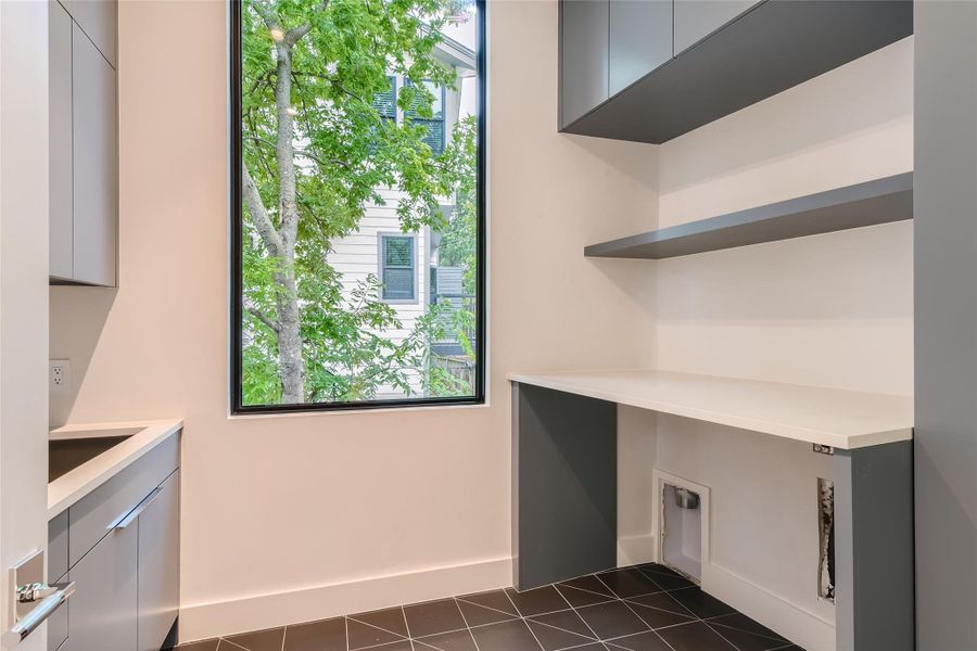 A well-appointed laundry area features practical shelving, counter space, and a bright window overlooking lush greenery. A well-appointed laundry area features practical shelving, counter space, and a bright window overlooking lush greenery.