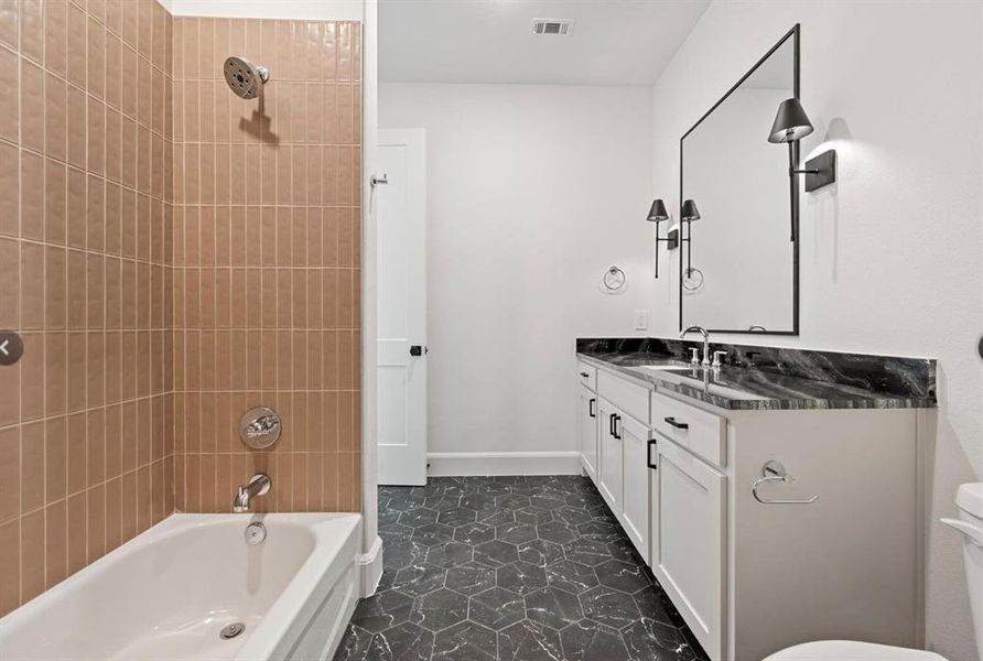 Full bathroom featuring vanity, toilet, tile patterned floors, and tiled shower / bath