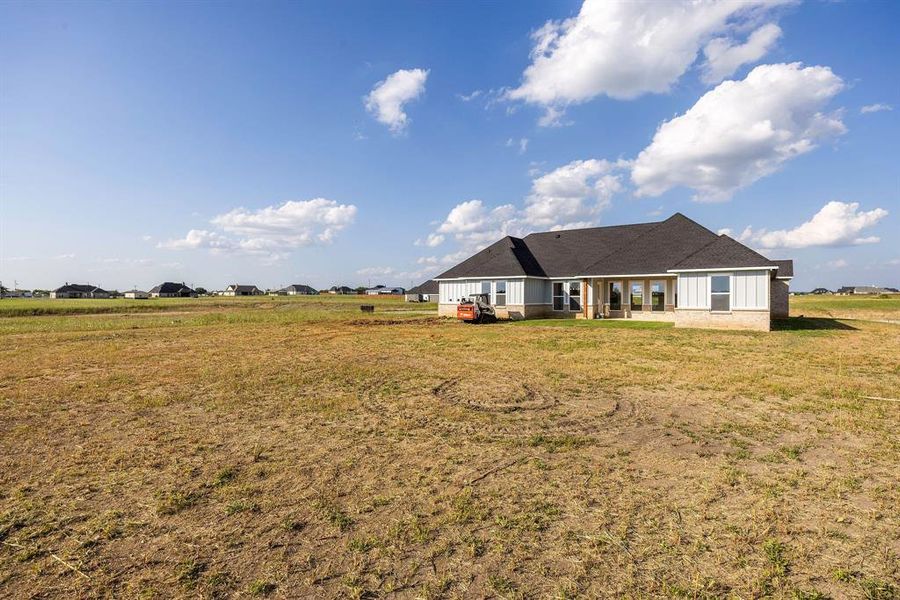 Back of house with a yard and board and batten siding Back of house with a yard and board and batten siding